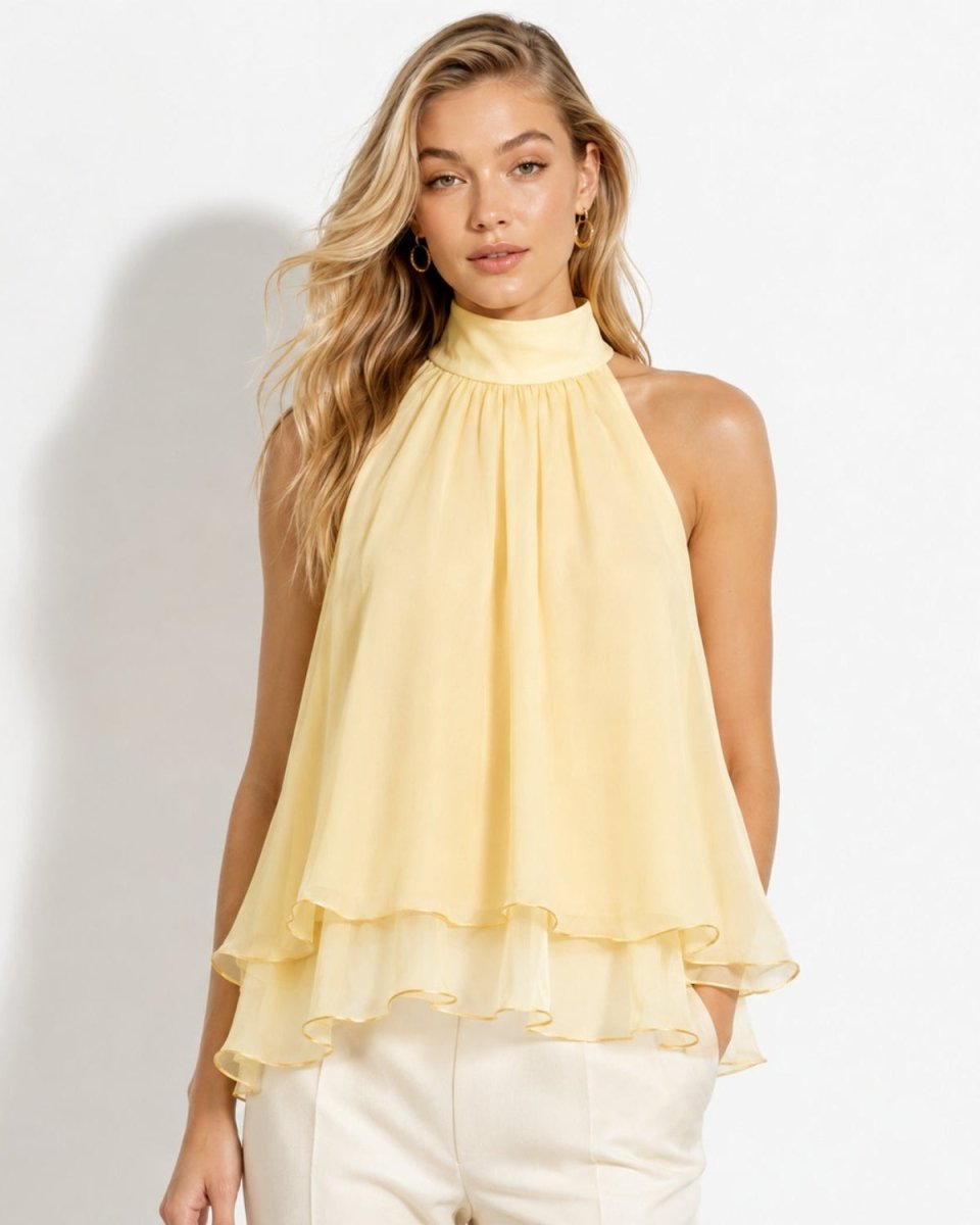 Front view of a blonde model wearing a pastel apricot chiffon tiered halter blouse with high neck and flowing ruffled layers