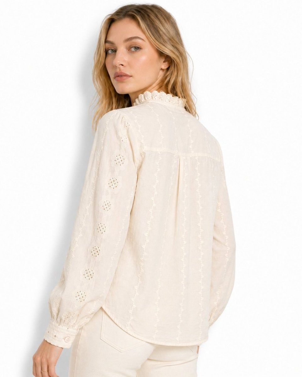 Back view of woman wearing an beige vintage-inspired blouse highlighting vertical embroidered floral accents and back yoke pleating.