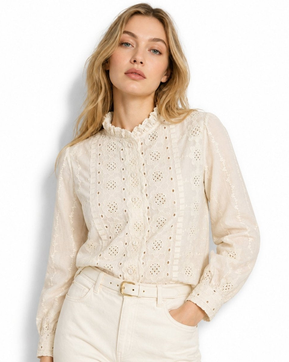 Half body shot of female model casually posing with hand in pocket wearing an affordable luxury beige  cotton eyelet button-down shirt.