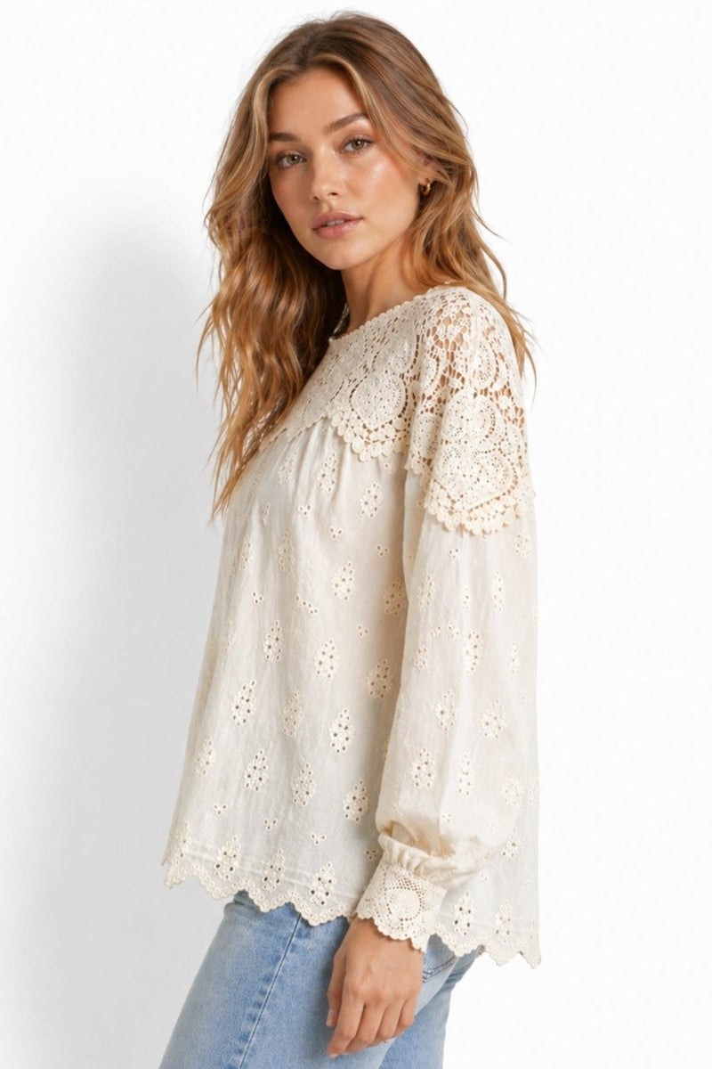 Side profile of woman in effortless bohemian off-white eyelet balloon sleeve top featuring intricate lace scalloped cuffs