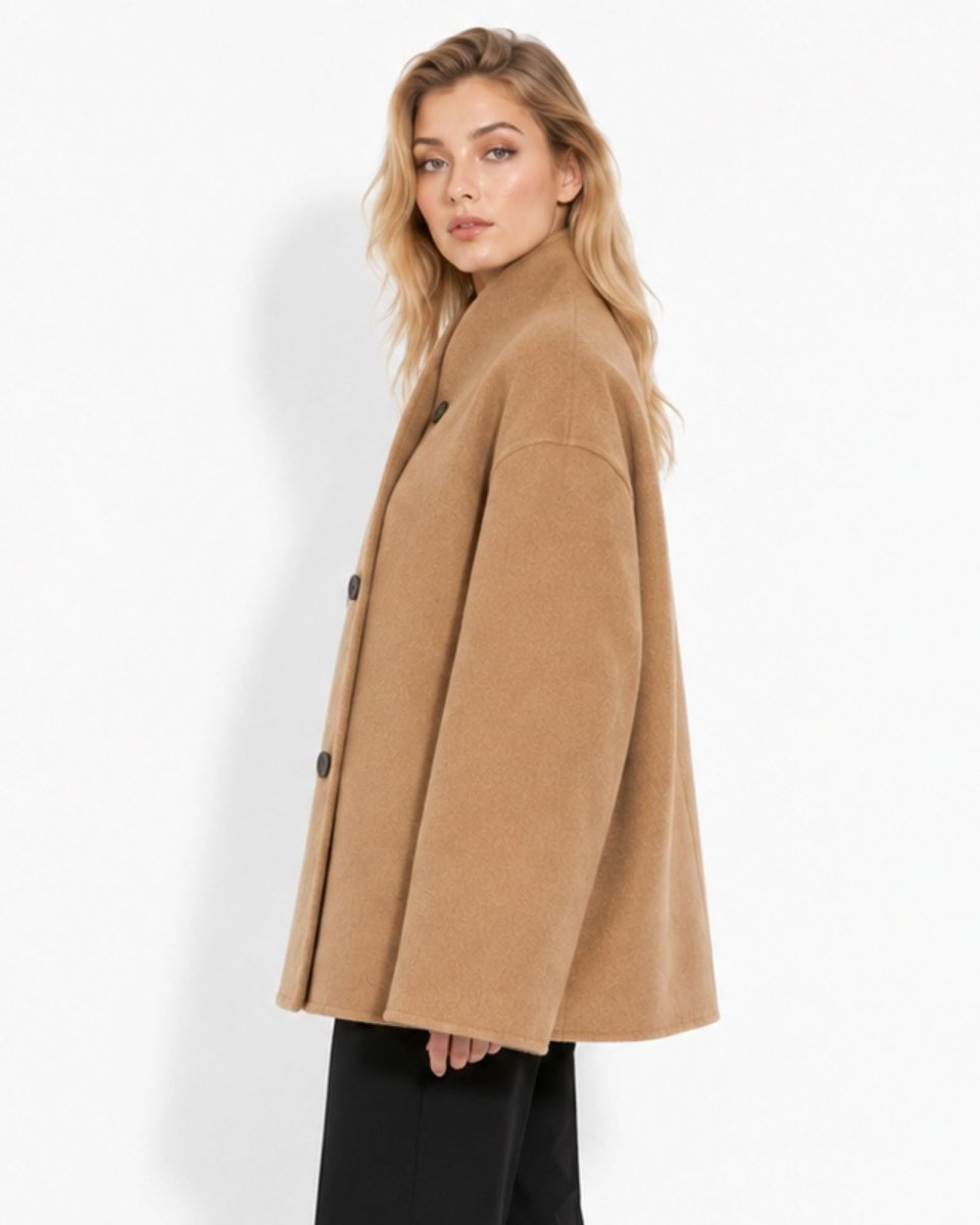 A woman modeling a camel-colored wool coat with dark buttons, shown from a side profile against a clean white studio background.