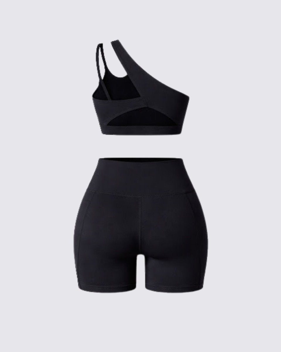 Flat lay back view of black matching workout set showing sports bra back strap details and biker shorts construction