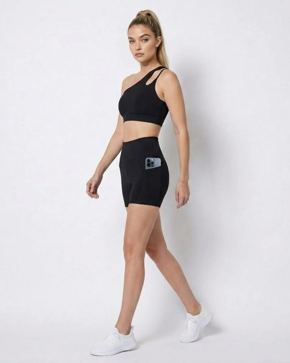 Side profile of woman walking in black high waisted biker shorts showing functional side phone pocket 