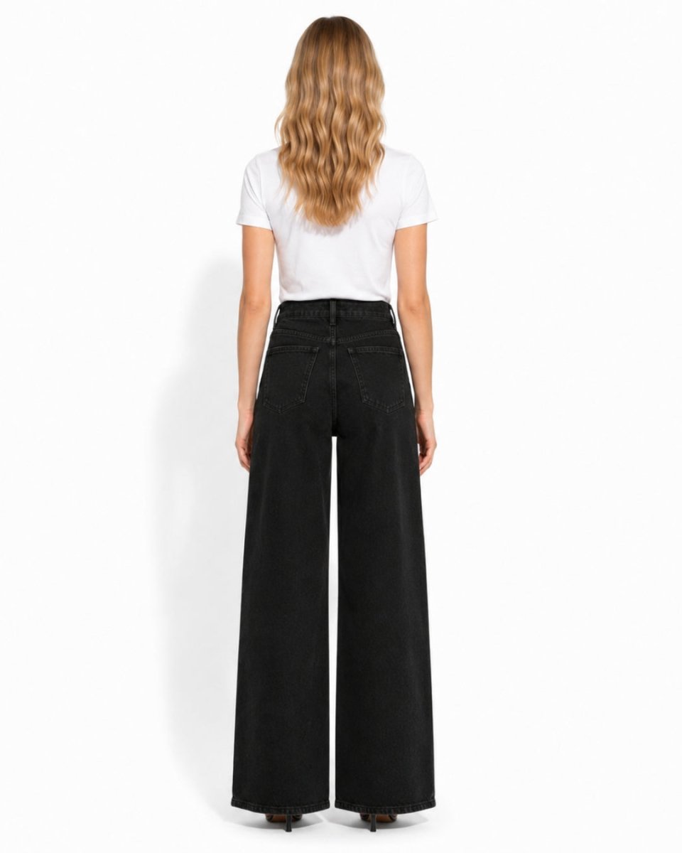 A woman shown from the back wearing a white short-sleeve t-shirt and high-waisted, wide-leg black denim jeans against a plain white studio background.