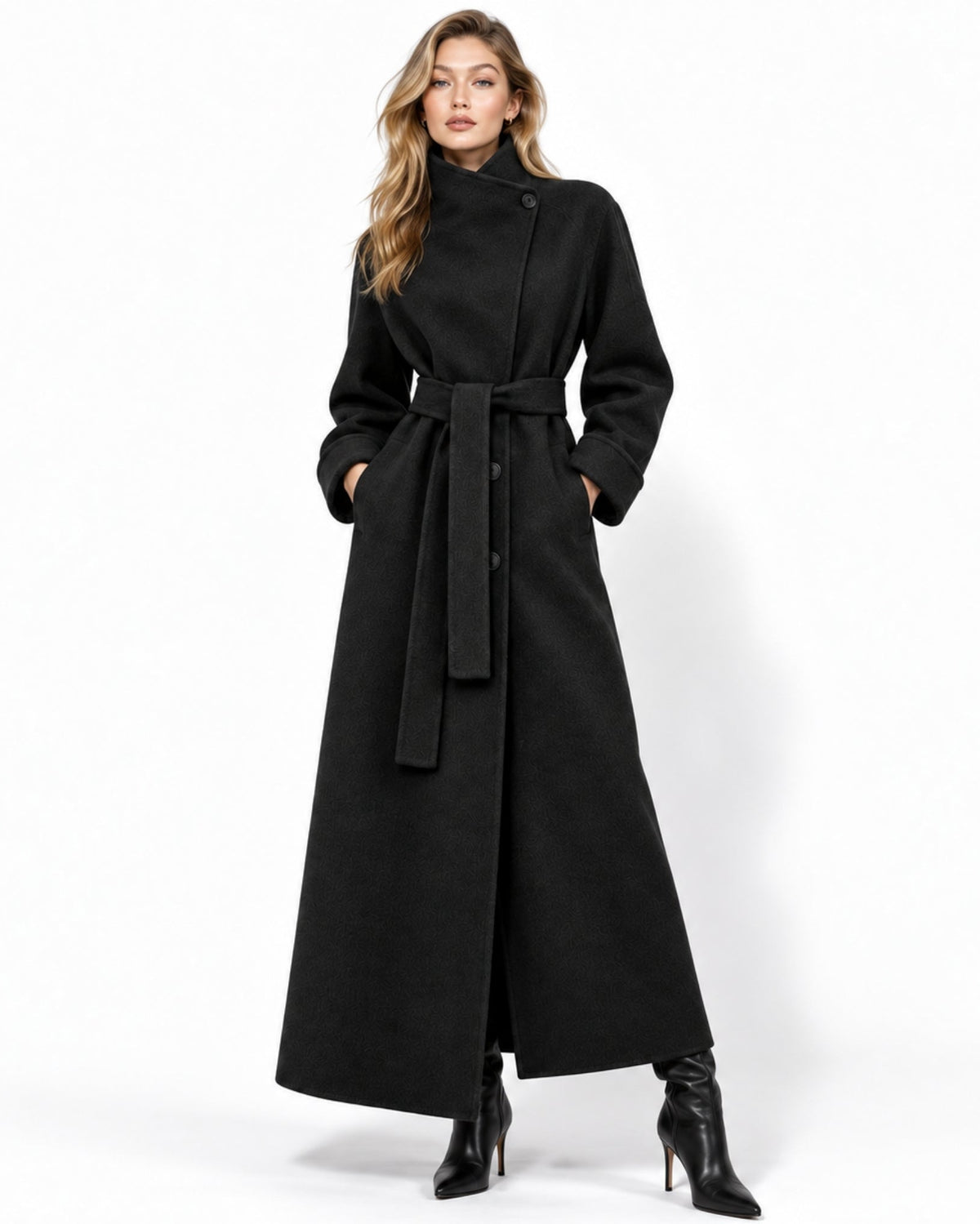 A woman modeling a long black wrap-style coat with a waist tie, shown against a plain white studio background.