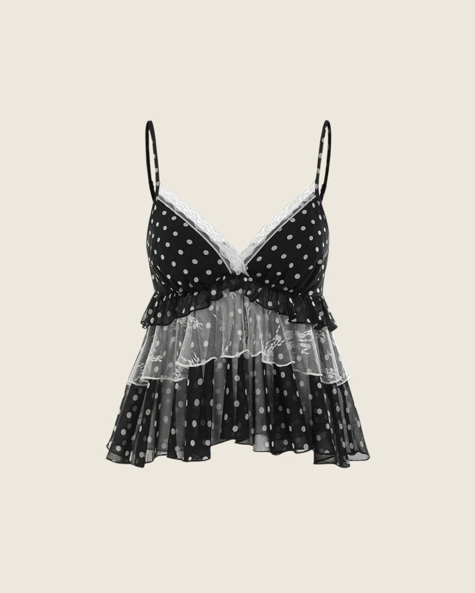 A black and white polka dot camisole top with thin spaghetti straps, a ruffled sweetheart neckline, and a layered ruffle skirt, shown against a solid light beige background.