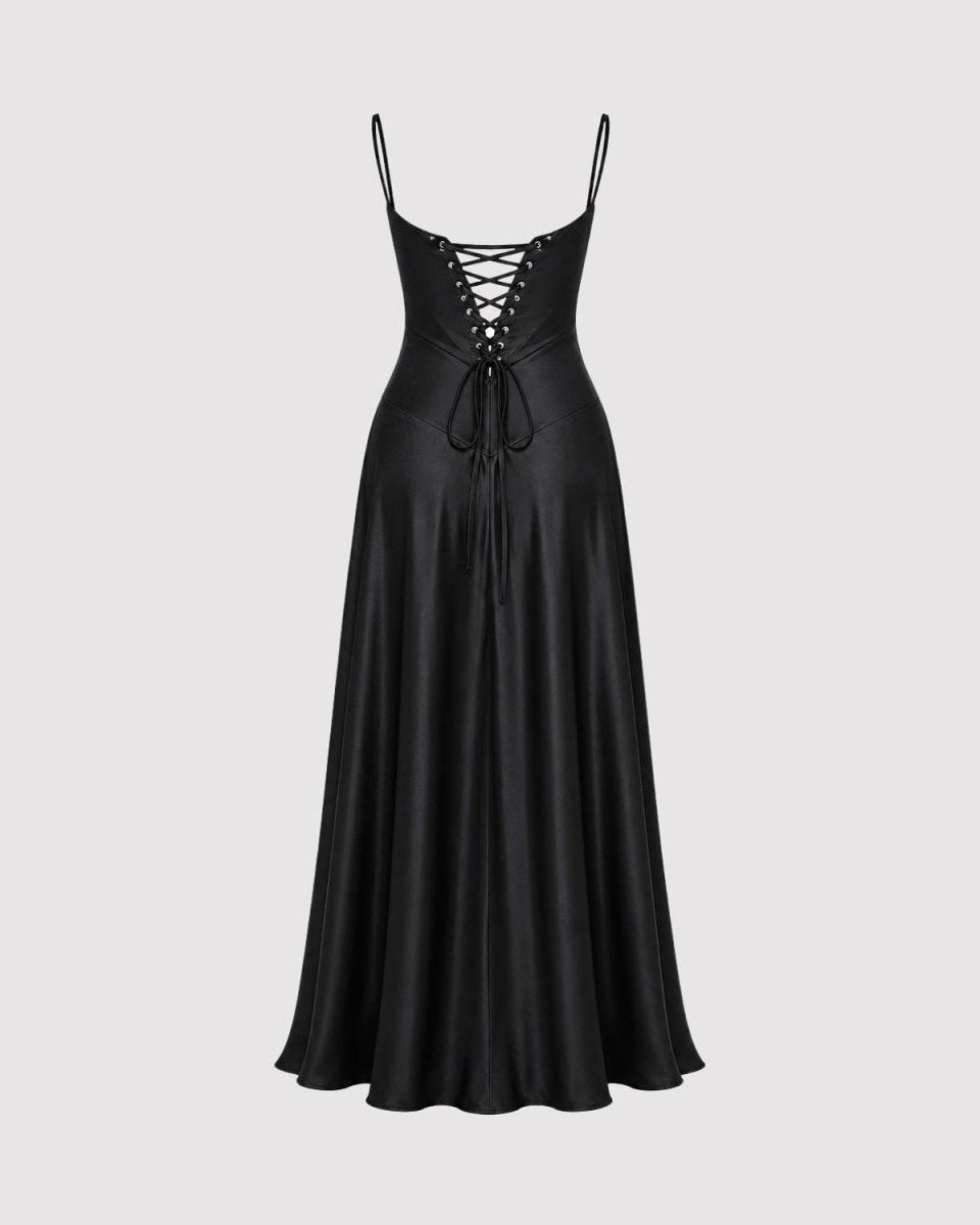 A black satin slip dress with thin spaghetti straps and a lace-up front, shown against a solid light gray background.