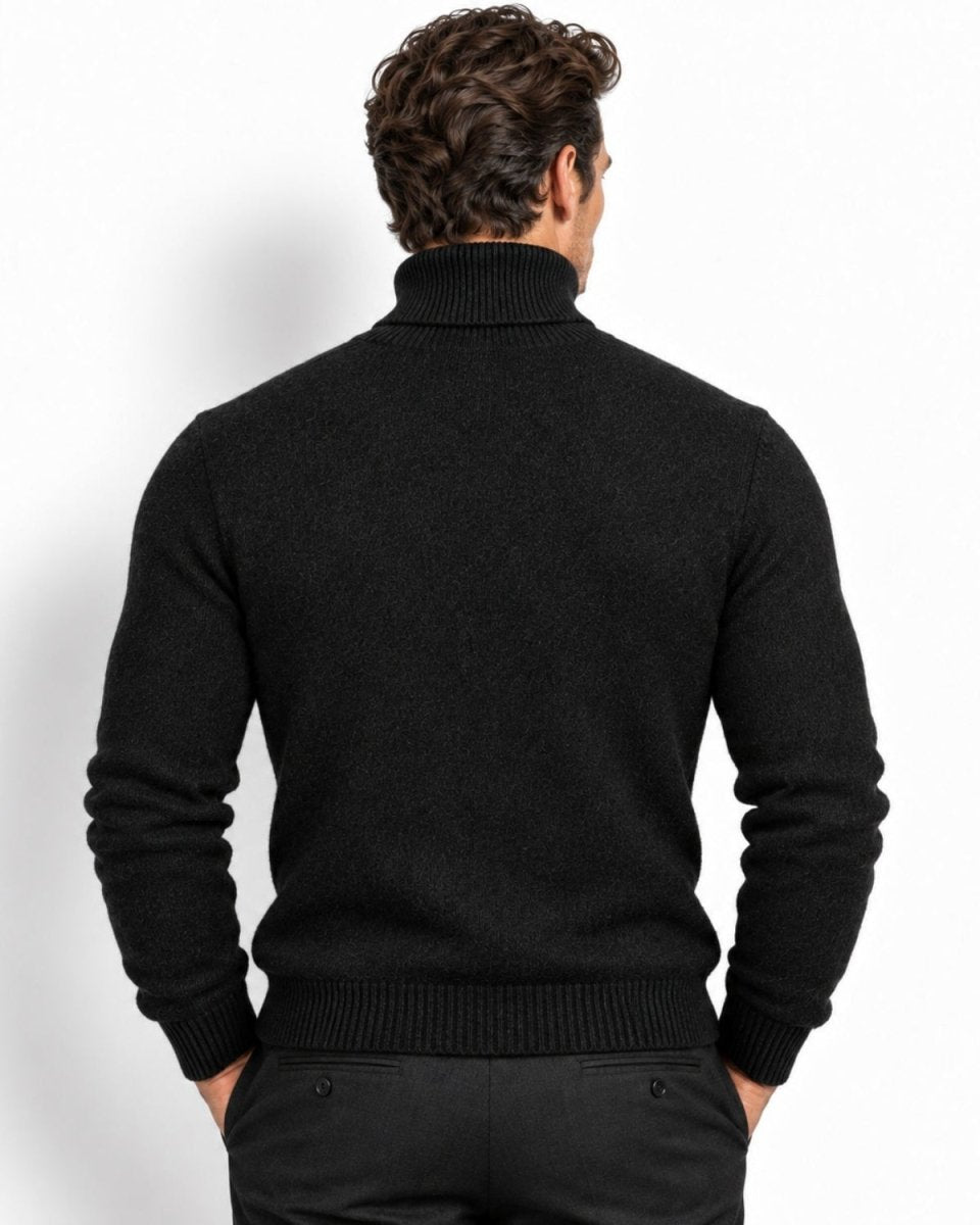 A man viewed from the back wearing a black knit turtleneck sweater and dark trousers against a clean white studio background.