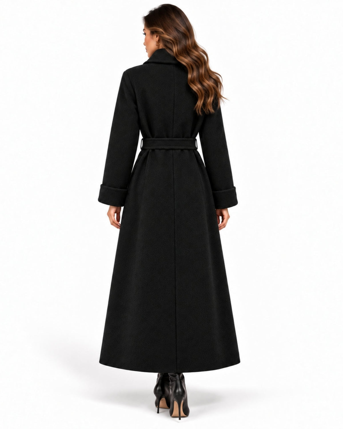 A woman viewed from the back wearing a long black belted coat with wide cuffs, paired with black high heels, against a plain white studio background.