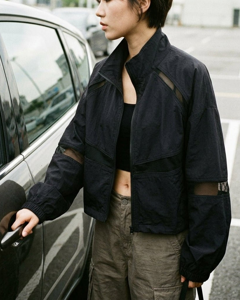 Casual mirror selfie showing how to style the Kouvr black Y2K windbreaker jacket with neutral pants