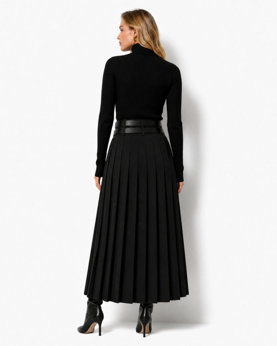 A woman shown from the back wearing a black long-sleeve mock-neck top, a high-waisted black pleated midi skirt with a matching black belt, and black ankle boots, against a plain white studio background.