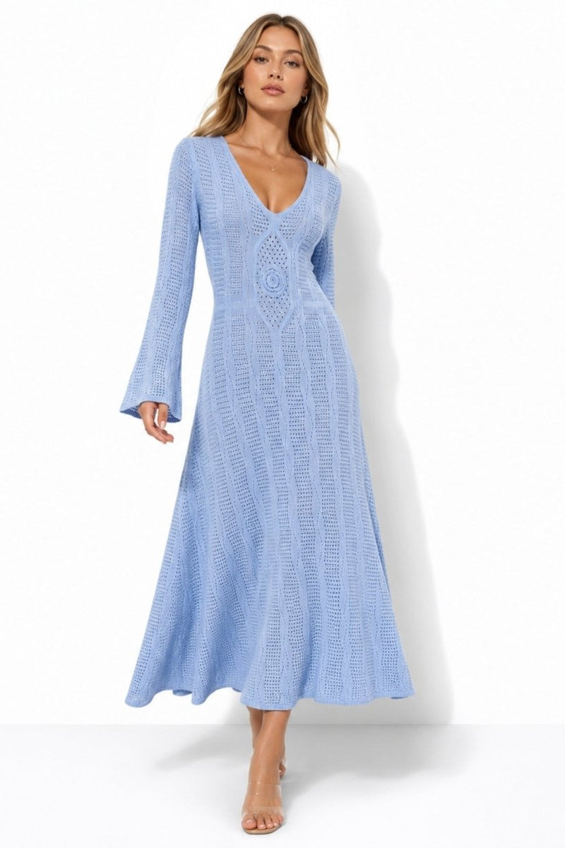Woman wearing a luxury light blue crochet long sleeve maxi dress with v-neck and bell sleeves walking forward against a white background.
