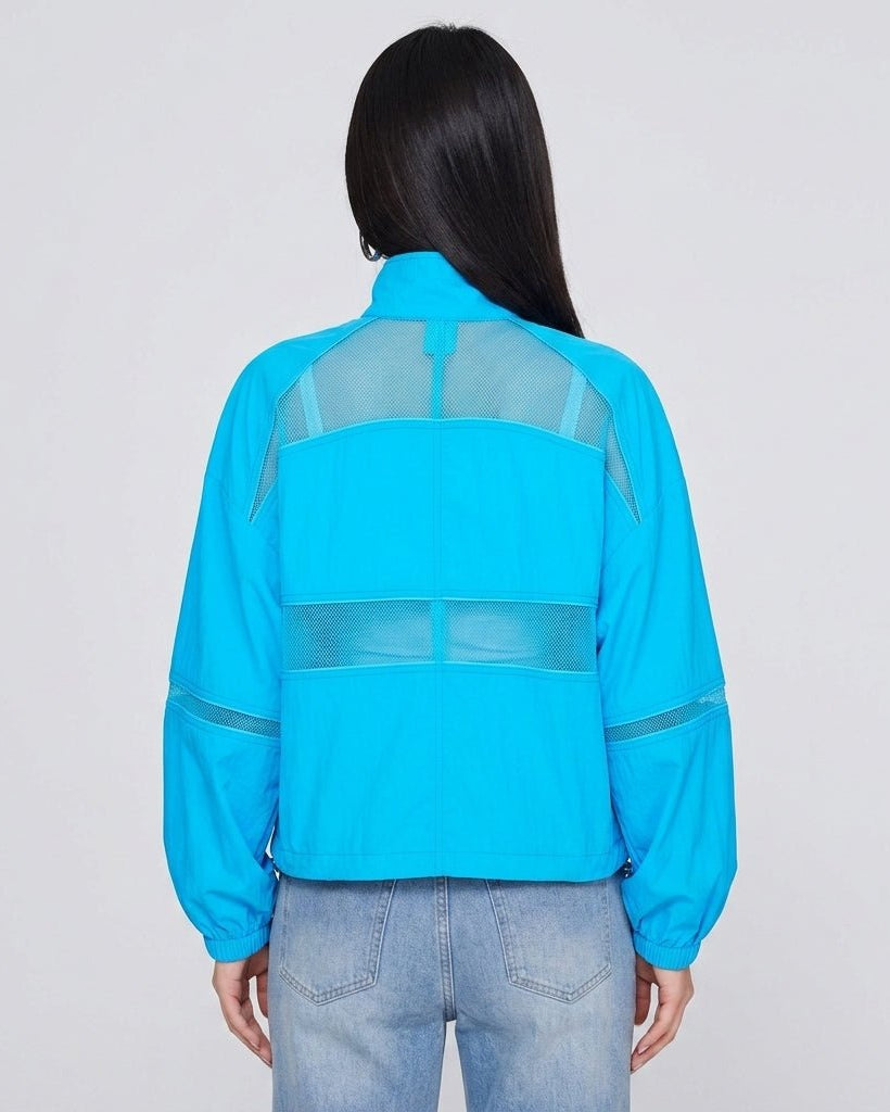 Back view of woman wearing Kouvr bright blue lightweight athleisure jacket showcasing horizontal mesh ventilation detailing.