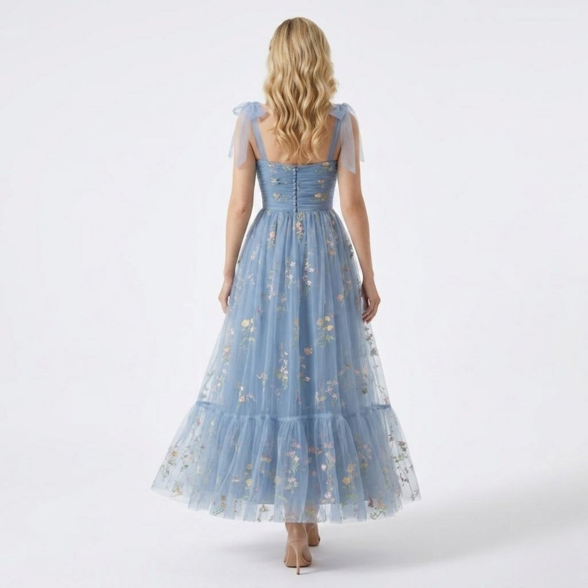 Back view of the Kouvr  blue floral tulle gown highlighting elegant decorative covered buttons and sheer tulle tie shoulder bows.