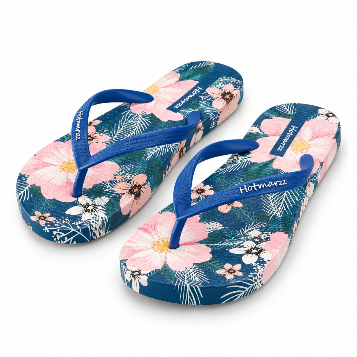 Top view of women's luxury navy blue flip flops featuring a tropical pink and white floral botanical print and soft blue straps.