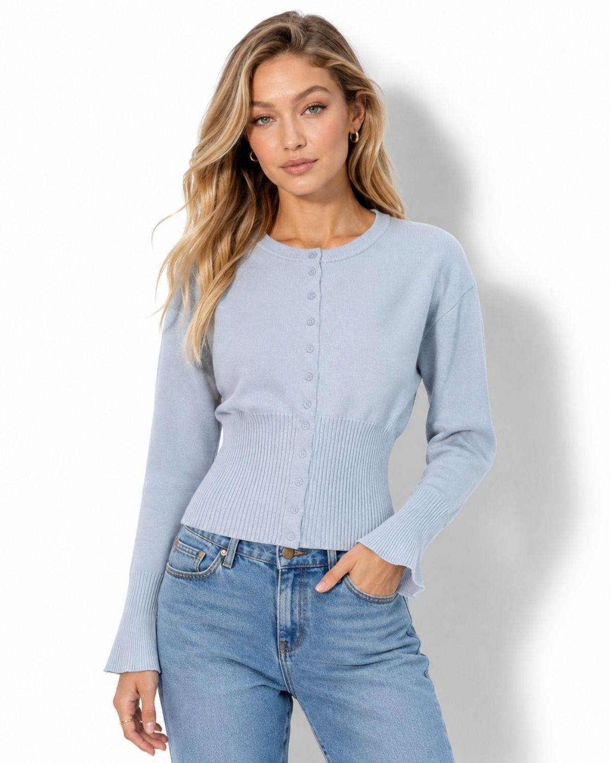 A woman modeling a light blue ribbed long-sleeve cardigan with a button-up front, paired with light-wash blue jeans, against a white studio background.