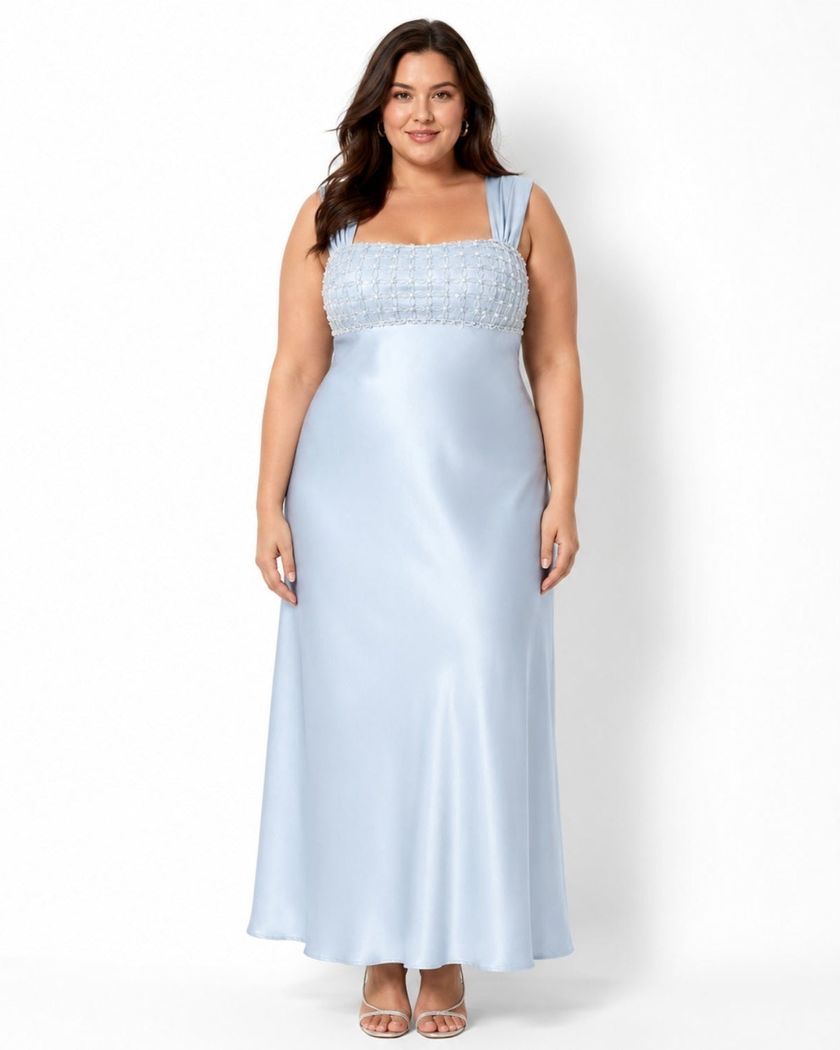 A woman modeling a light blue satin maxi dress with a textured, embellished square neckline, standing against a plain white studio background.