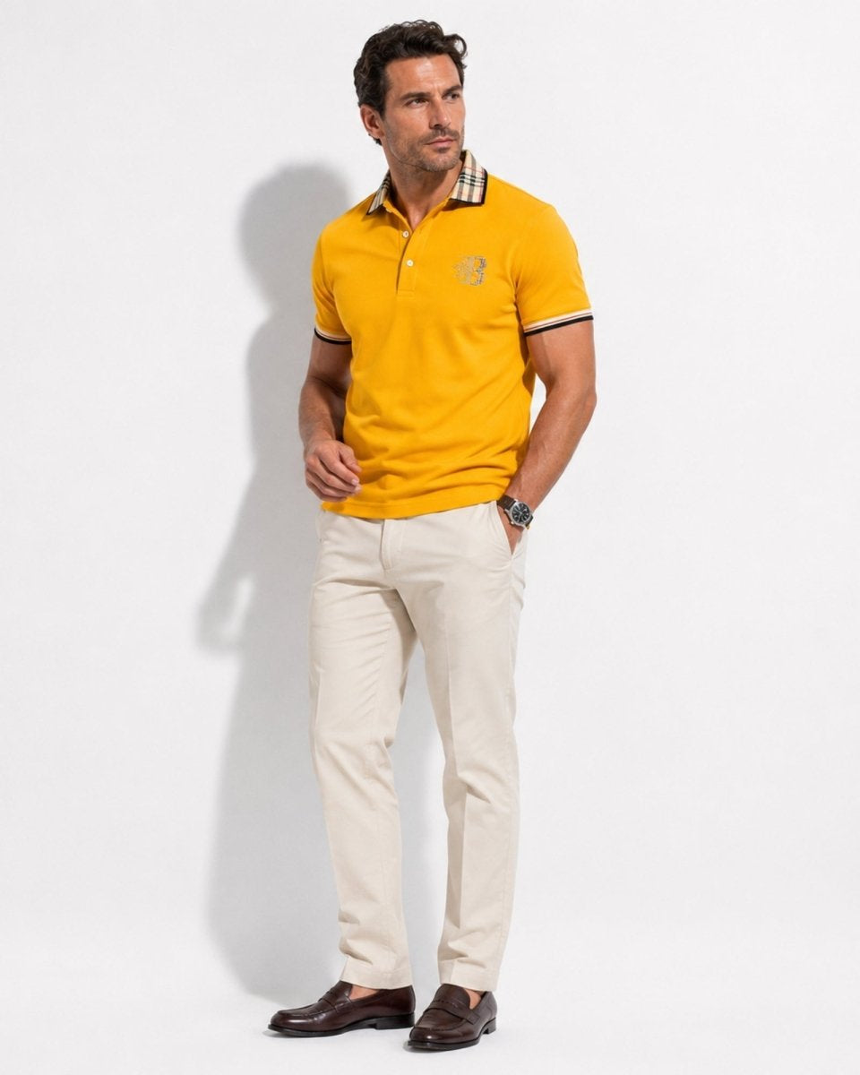 Man wearing a yellow polo shirt and white pants on a light gray background