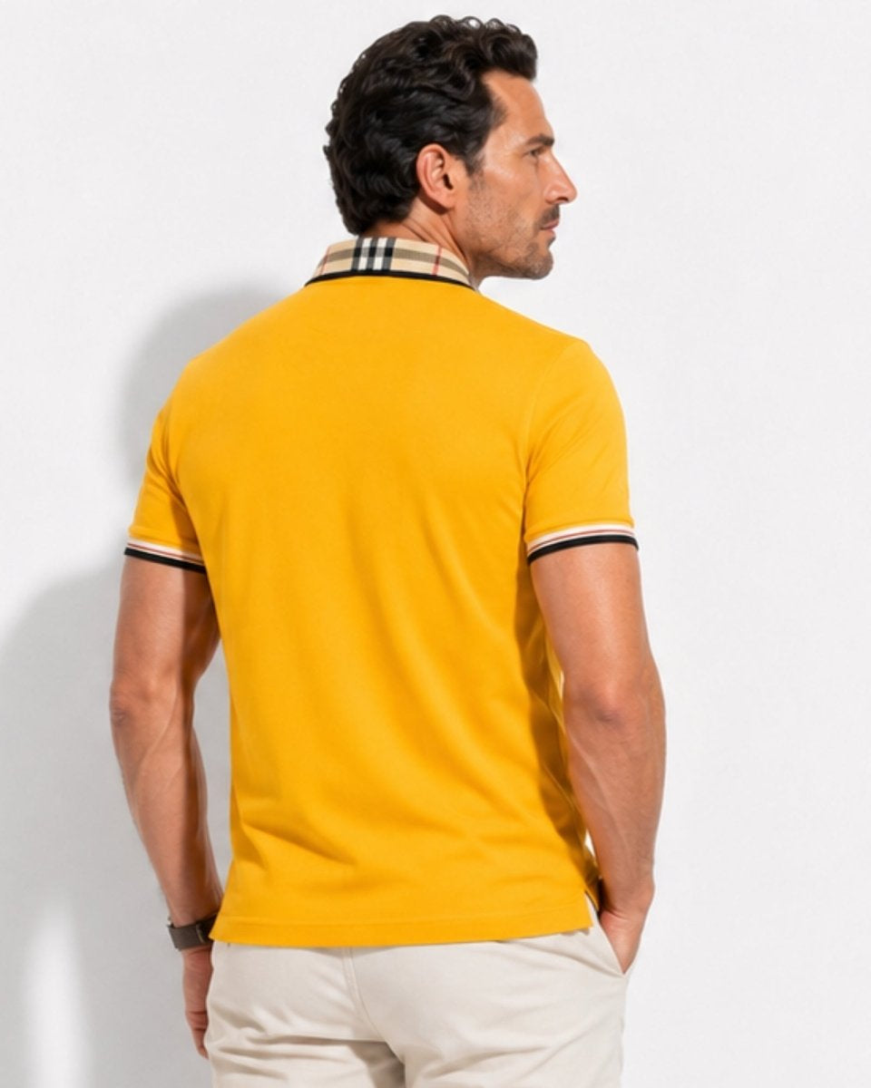 Man wearing a yellow polo shirt with a checkered collar against a white background