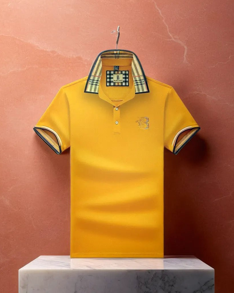 Yellow polo shirt with plaid collar on a hanger against a pink background