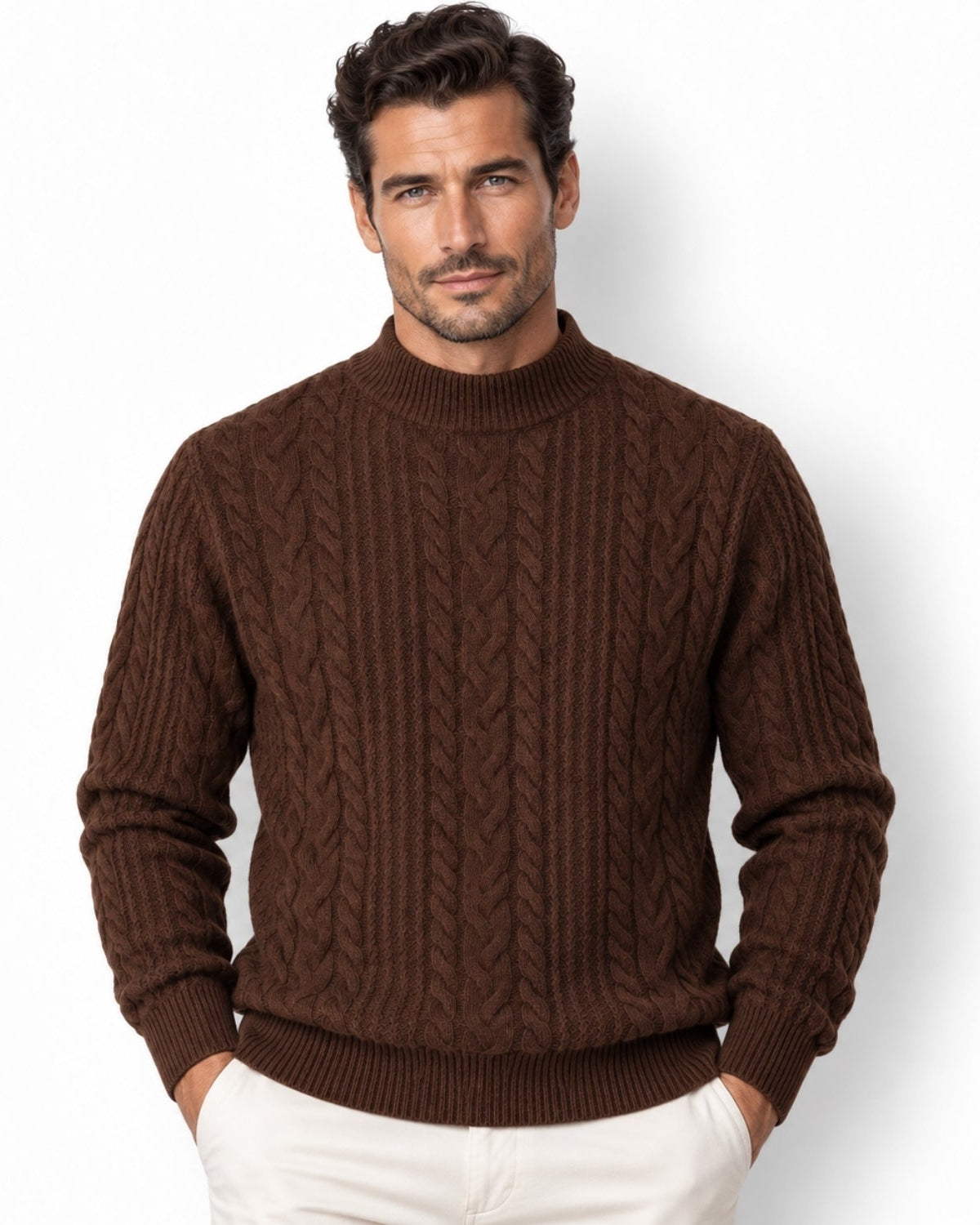 A man wearing a dark brown cable-knit mock neck sweater and off-white trousers, standing against a plain white studio background.