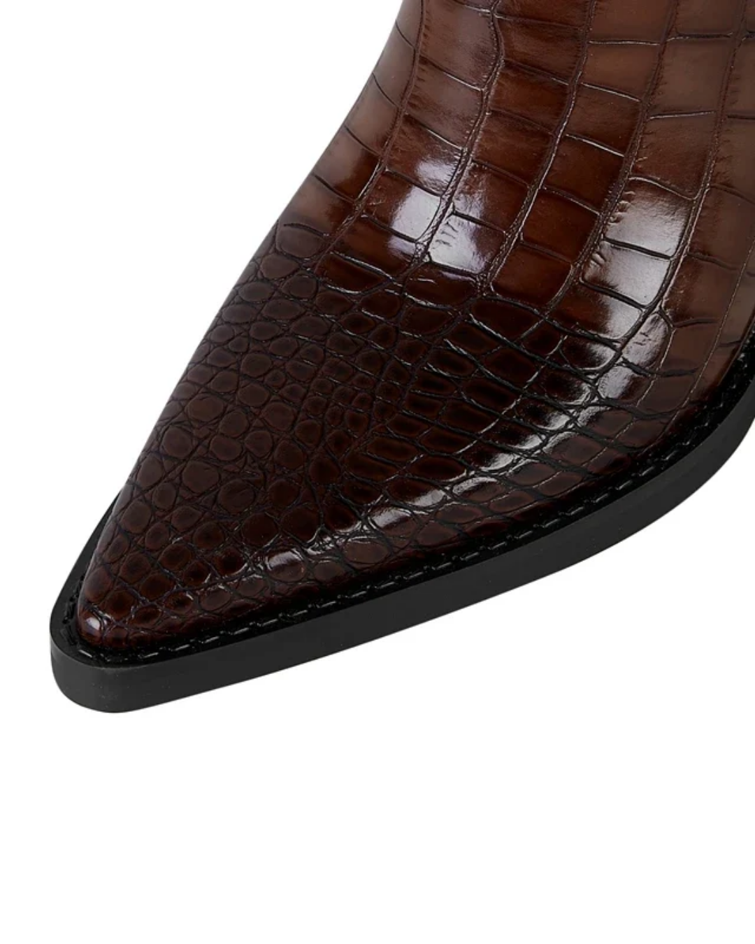 Close-up of a pointed-toe boot featuring a glossy brown crocodile-embossed leather upper and a black sole, shown against a plain white background.