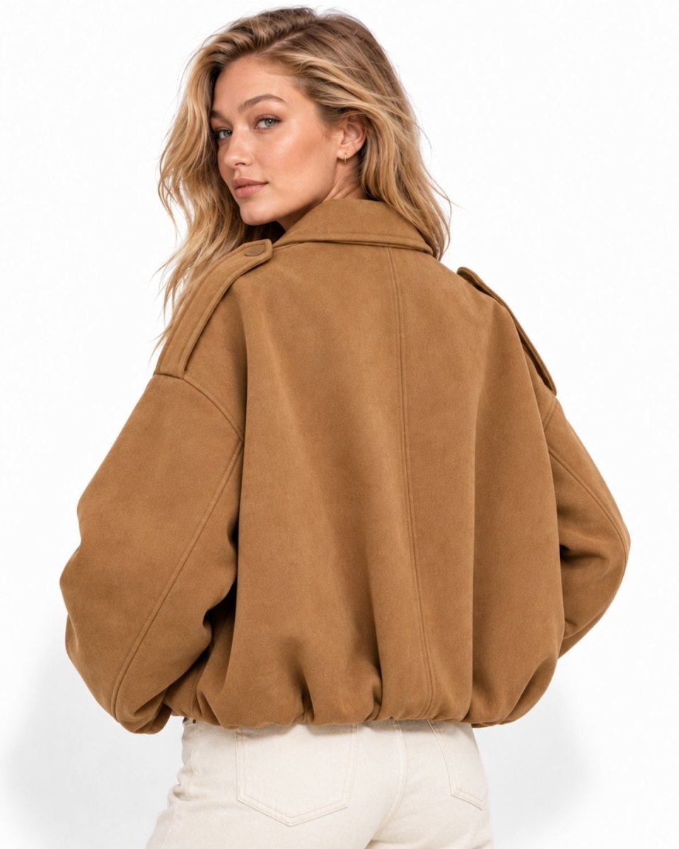 A woman wearing a cropped camel brown suede jacket, shown from the back, paired with off-white pants against a clean white background.