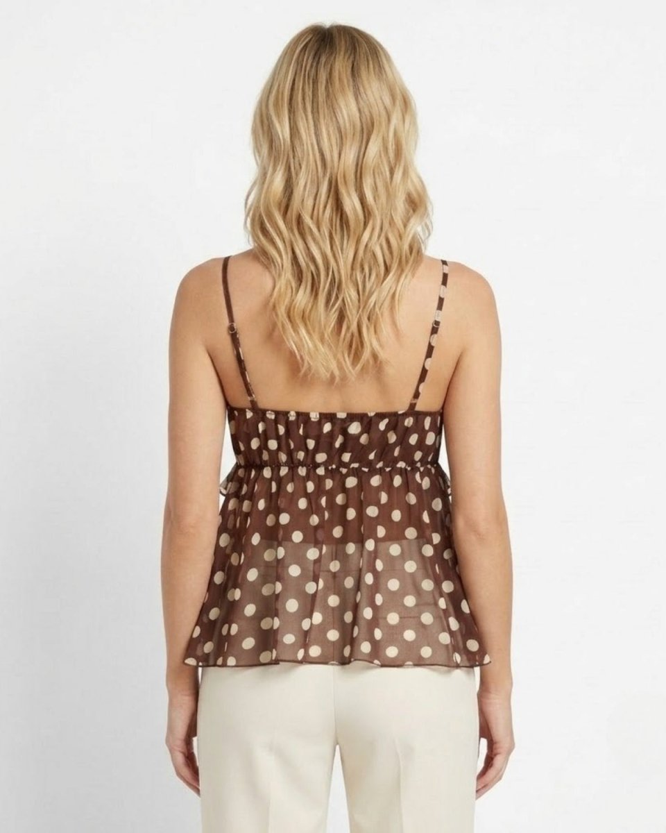 A woman viewed from the back wearing a brown camisole top with beige polka dots and thin straps, paired with light beige pants, against a plain white background.