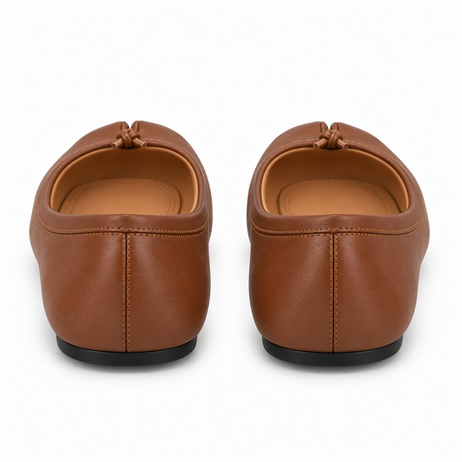 A pair of brown leather slip-on shoes shown from the back, featuring a small leather tassel detail at the top and black soles, set against a plain white background.