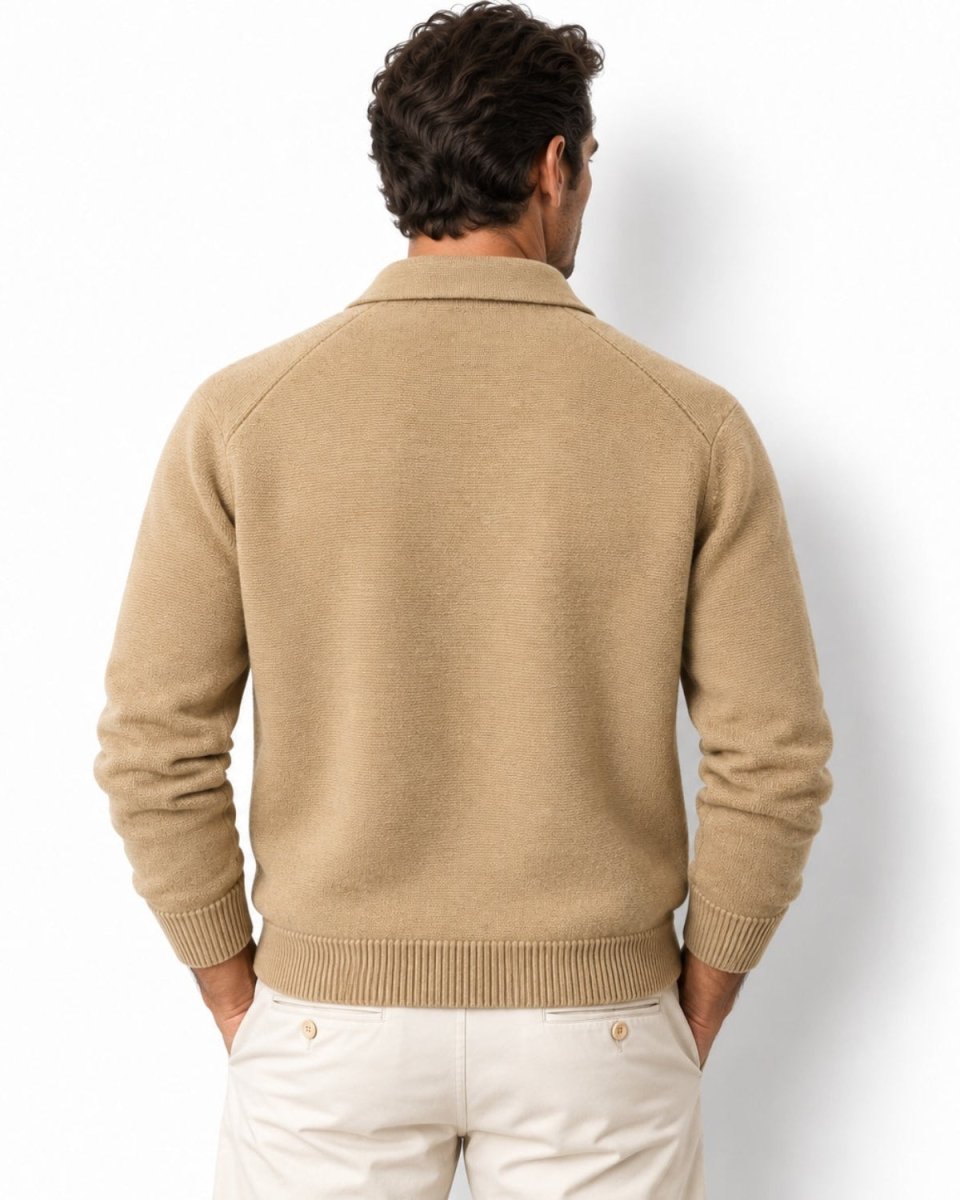 A man viewed from behind wearing a beige knit sweater with raglan sleeves and cream pants, set against a plain white studio background.