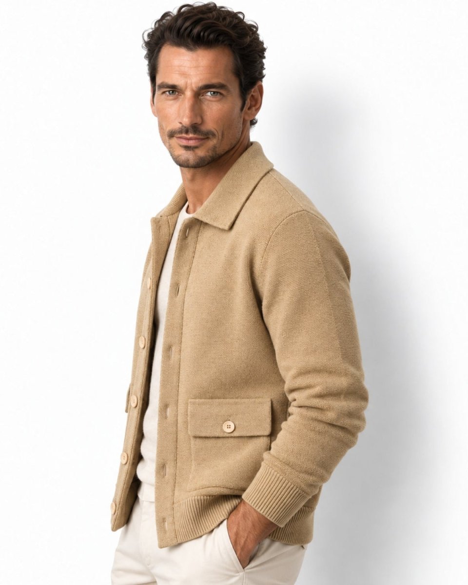 A man wearing a camel knit button-front cardigan over a white shirt and white pants, photographed against a clean white studio background.