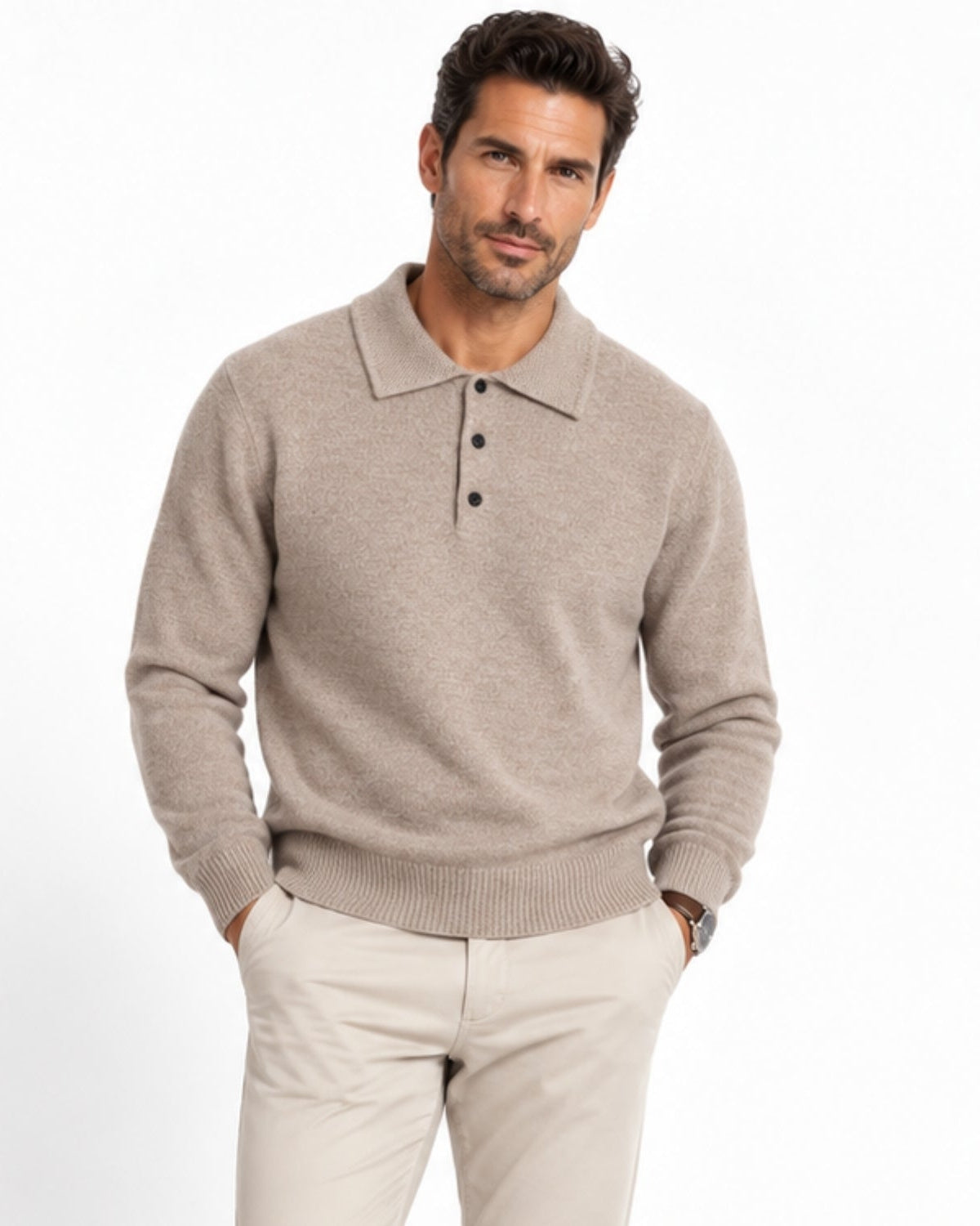 A man wearing a light beige knit polo sweater with a three-button placket and cream trousers, standing against a plain white studio background.