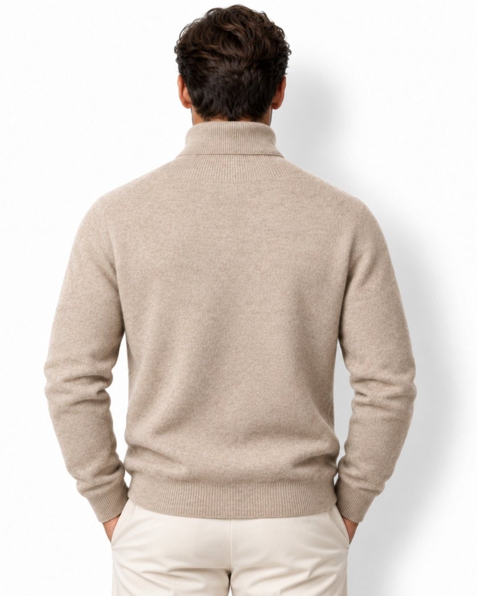 A man viewed from behind wearing a light camel knit mock neck sweater and cream trousers, standing against a plain white background.
