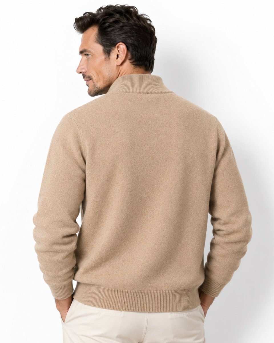 A man shown from the back wearing a light camel knit sweater with a mock neck and ribbed hem, paired with off-white trousers, against a plain white studio background.