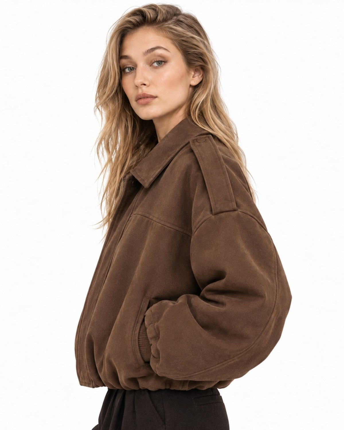 A woman wearing a brown oversized cropped jacket with a collar and front zipper, paired with black pants, photographed against a plain white background.