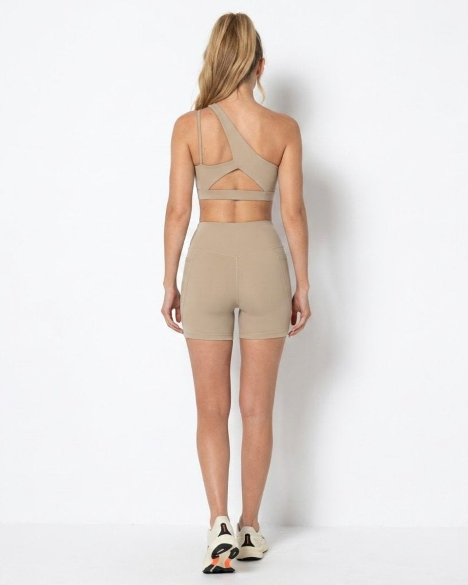 Back view of khaki workout set highlighting the angular back cutout on the sports bra and form fitting biker shorts.