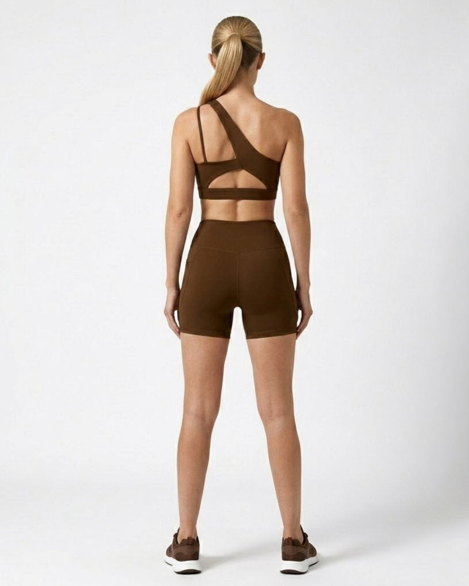 Back view of dark brown activewear set highlighting strappy cutout sports bra and high waisted shorts