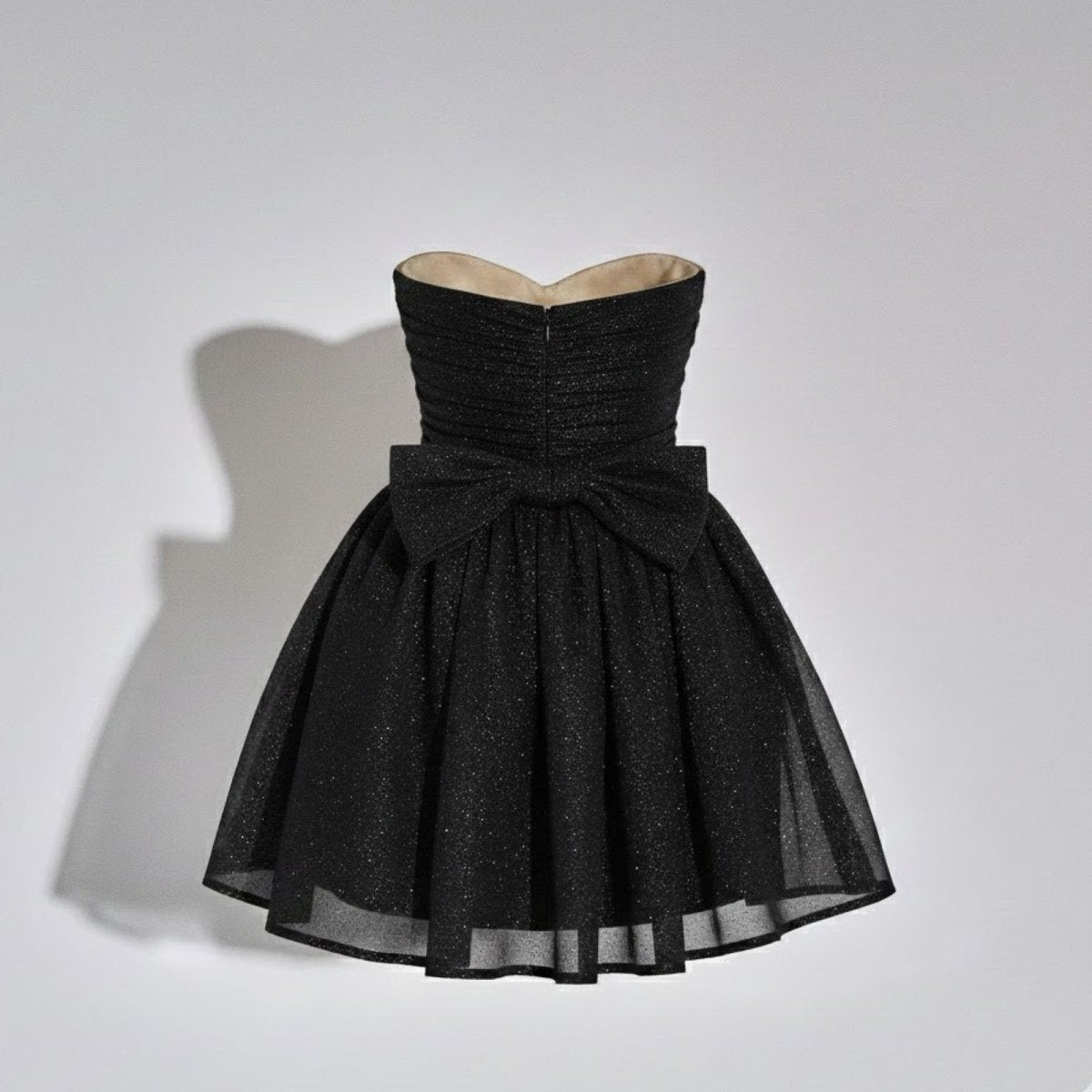 Product-only photo showing the back of the Kouvr glitter mini dress, with a close-up on the large statement bow detail.
