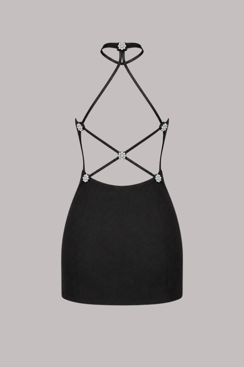 A black halter-neck mini dress with crisscrossing strappy details across the chest and waist adorned with small rhinestone embellishments, shown against a solid gray background.