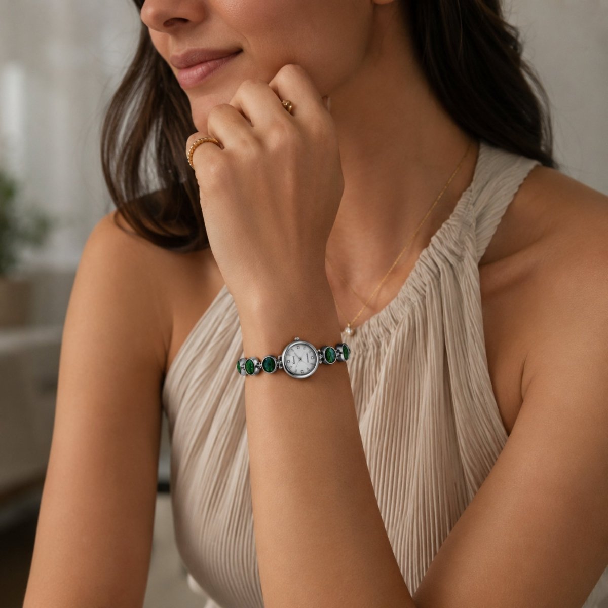  Beautiful woman wearing a pleated beige halter top elegantly modeling the silver Kouvr vintage green stone bracelet watch on her wrist.