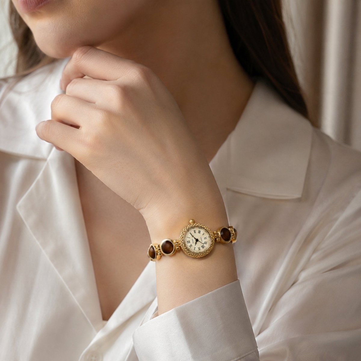 Elegant woman wearing a white silk blouse and the Kouvr vintage gold dress watch with tiger's eye stones, showcasing sophisticated office wear styling.