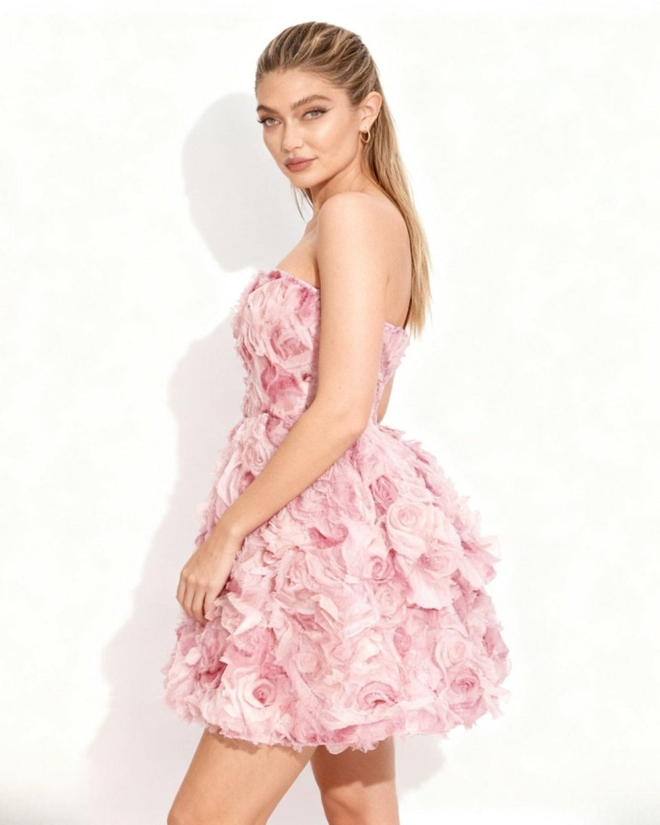 Side profile of a model in a short pink floral appliqué cocktail dress by Fenlo Form.