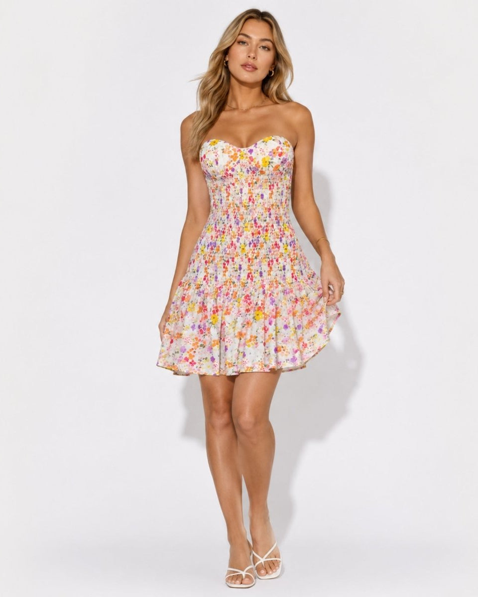 Beautiful woman modeling a luxury floral strapless smocked mini dress with sweetheart neckline and tiered ruffle skirt by Kouvr.