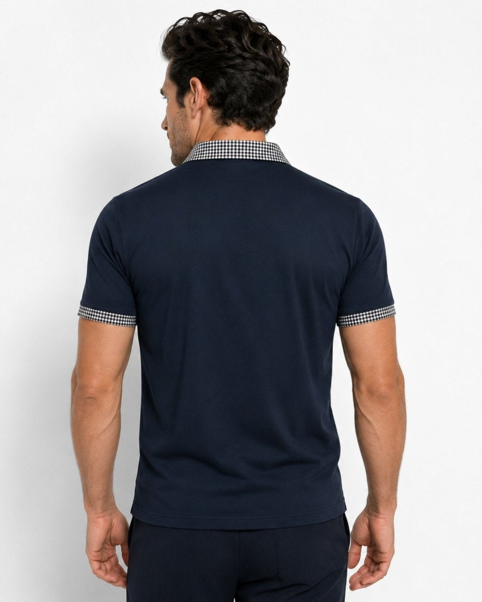 Man wearing a navy blue polo shirt with checkered collar and cuffs on a white background