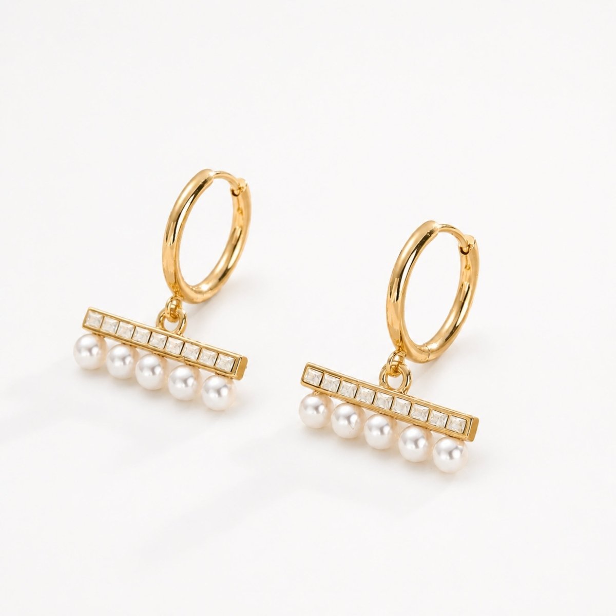 Premium gold huggie hoop earrings featuring a geometric crystal bar and five elegant dangling pearls isolated on a crisp white background.