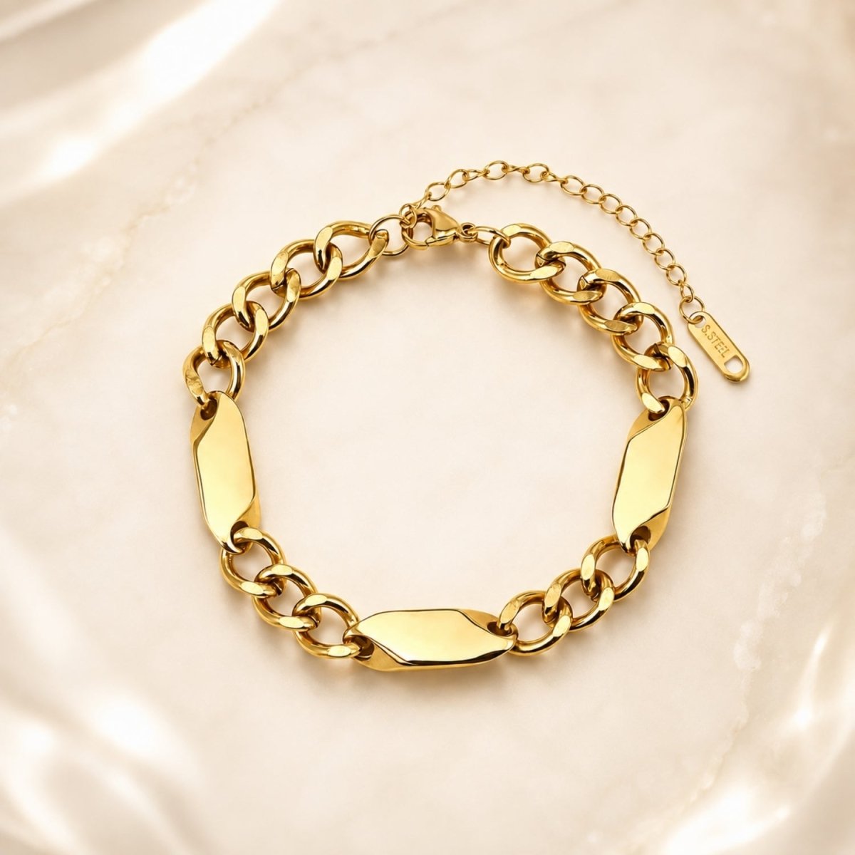 Luxury gold tone chunky chain bracelet resting elegantly on soft, luminous silk fabric