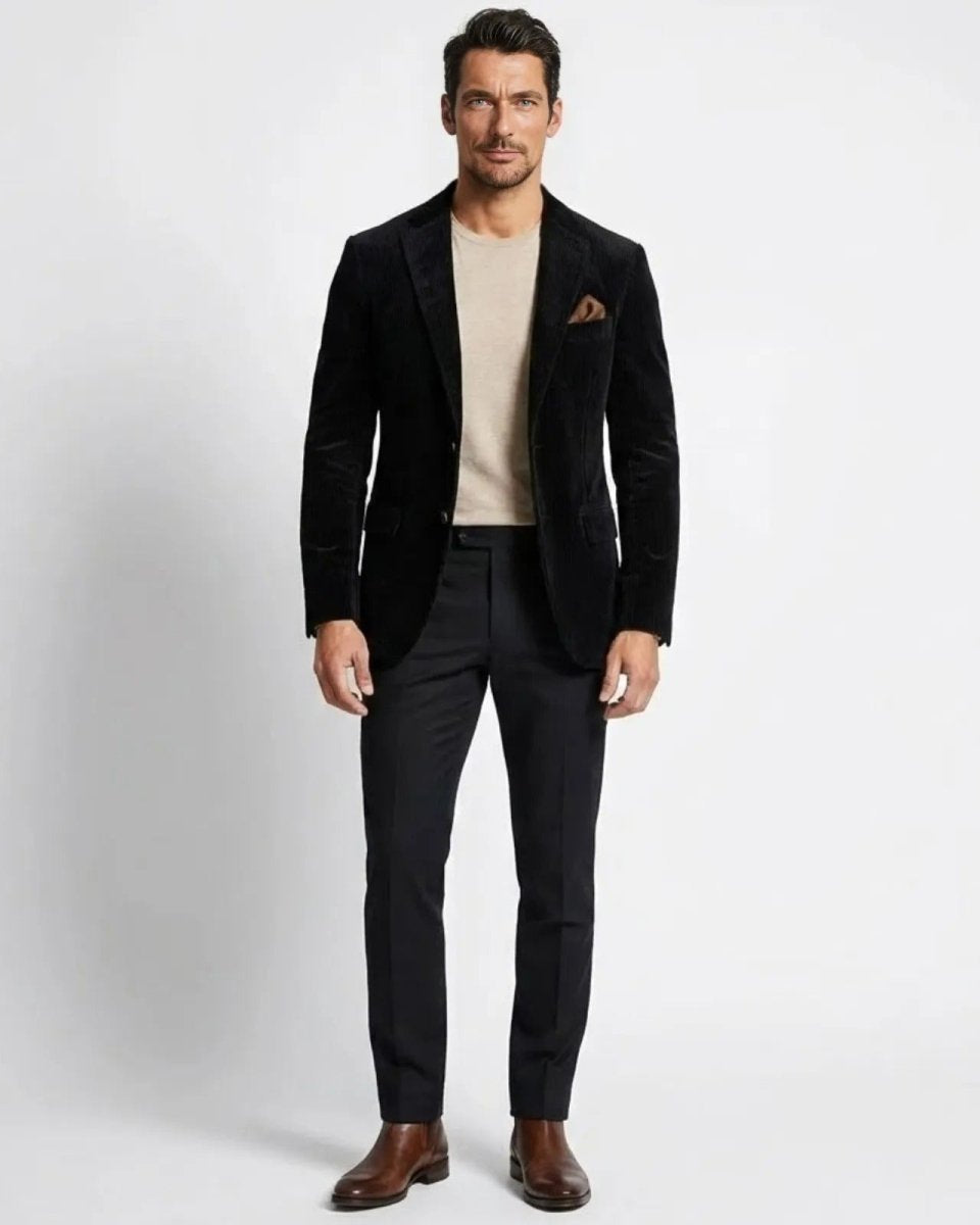 Model wearing the Grady men's slim fit black corduroy blazer with a beige crewneck sweater and black trousers. 