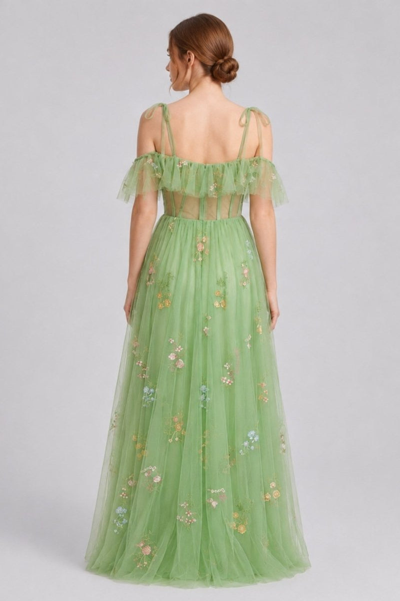 Back view of model in green floral tulle maxi dress highlighting delicate tie-shoulder straps and sheer corset back detailing.