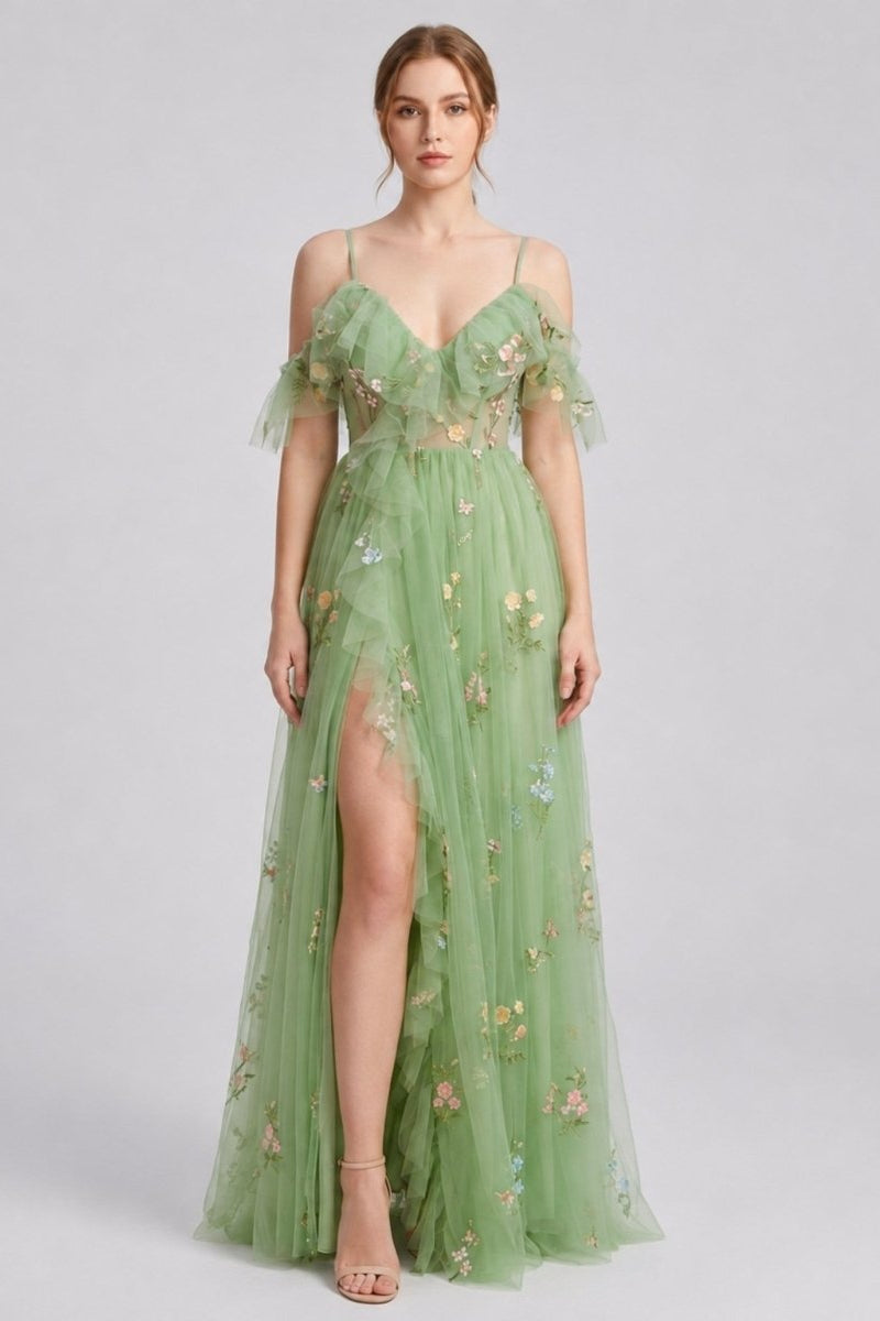 Elegant woman wearing a green floral embroidered tulle maxi dress with corset bodice and high leg slit, front full body view.