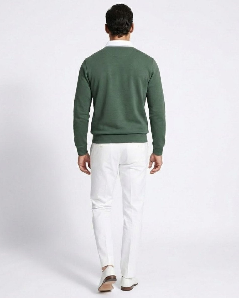 Back view of a man wearing the green knit polo sweater with white trousers.